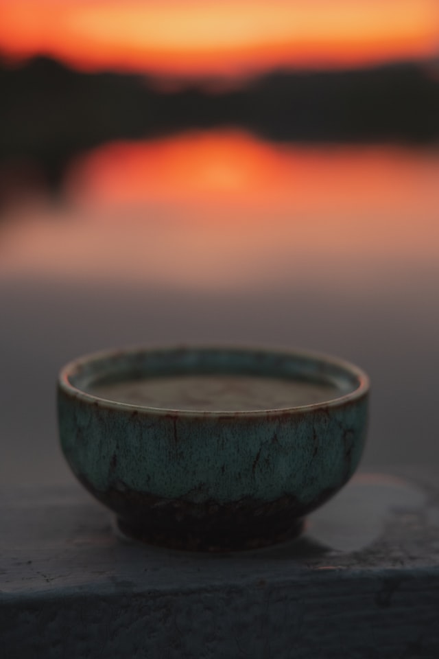 Tea cup with tea at sunrise overlooking beautiful lake